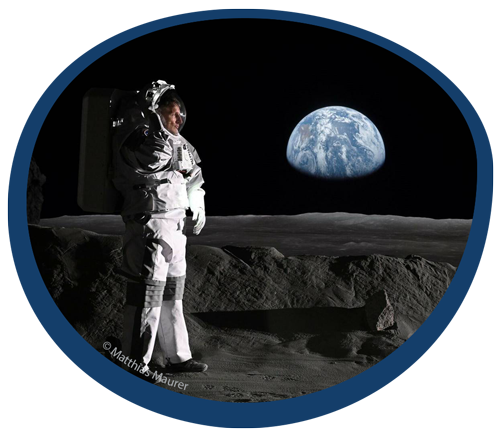 Matthias Maurer in einem Astronautenanzug auf einer Mondoberfläche, im Hintergrund die Erde